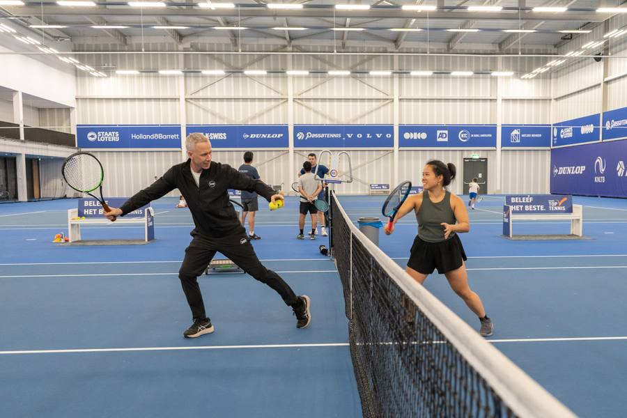 Volwassenen spelen samen een rally tijdens indoor tennisles voor beginners — 359.tennis