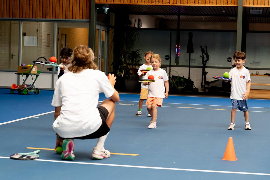 Coach begeleidt jonge kinderen bij hun eerste tennisles indoor op NTC Amstelveen — 359.tennis
